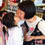 参加此次公益活动的福州一名女童为母亲送上康乃馨花束后，再献深情的一吻，表爱意。　记者刘可耕 摄 - 台湾新闻-中国新闻网