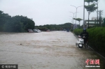 资料图：台湾暴雨来袭，骑摩托车者推车前行。图片来源：视觉中国 - 台湾新闻-中国新闻网